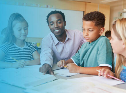 Three students and a teacher working together at a table.